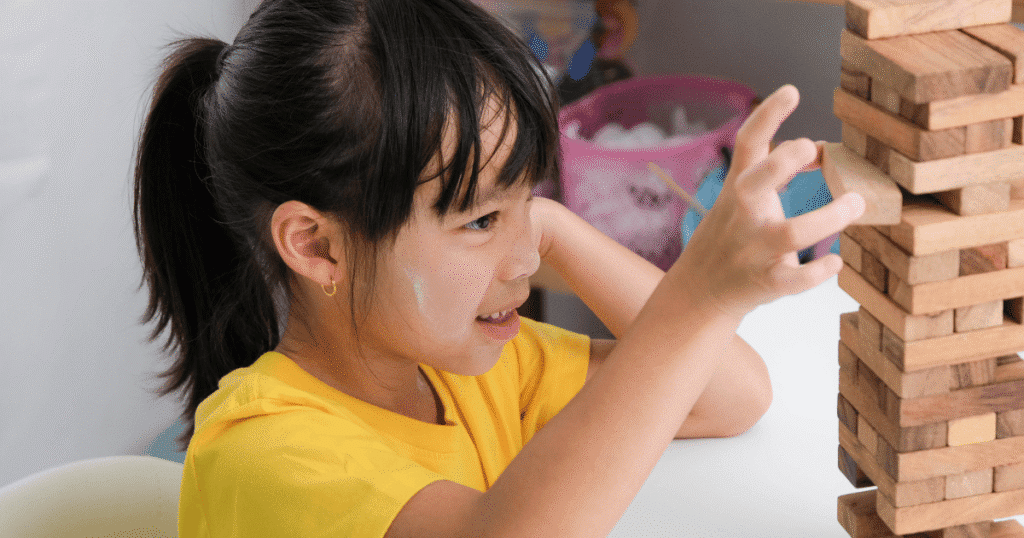 Niña jugando a construir con bloques, ilustrando la juegoterapia como herramienta clave en la psicología infantil para la expresión emocional.